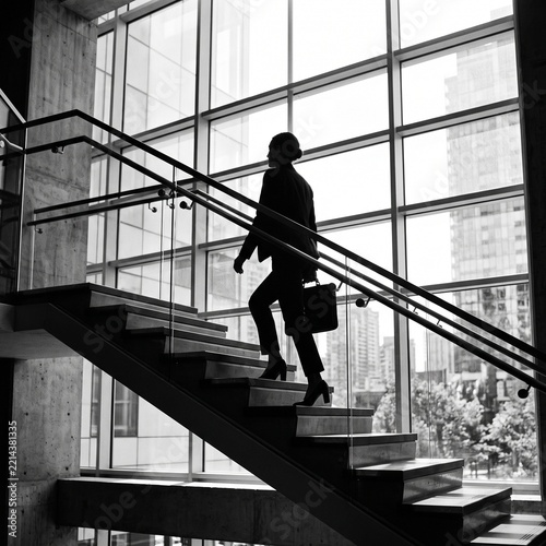 Silhouette of Businessperson Walking Up Glass Staircase