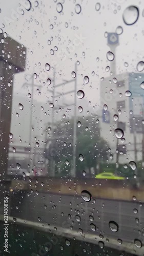 Raindrops on a car window with a blurred urban cityscape of Bangkok Thailand beyond, creating a moody atmosphere for rainy weather, transportation, travel, and environmental ,extreme unpredictable