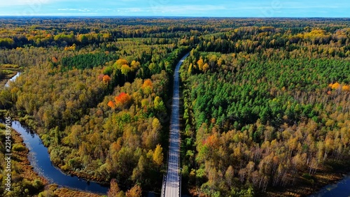 Aerial view of railway bridge surrounded by vibrant autumn foliage and winding river