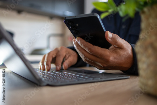 Person multitasking by typing on a portable keyboard and holding a smartphone, managing multiple digital tasks for efficient work and connectivity