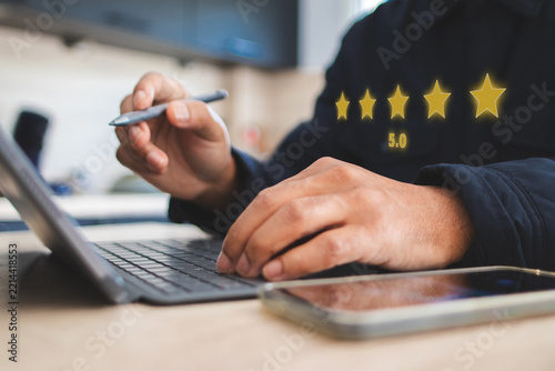 Person interacting with a tablet keyboard while giving a five star rating and 5.0 score, symbolizing customer satisfaction, excellent service, and positive online feedback