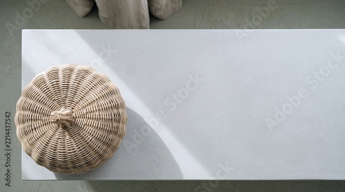 Woven rattan pumpkin decor rests peacefully on smooth white console table surface in bright modern interior. Top view flat lay composition highlights natural wicker texture and copy space.