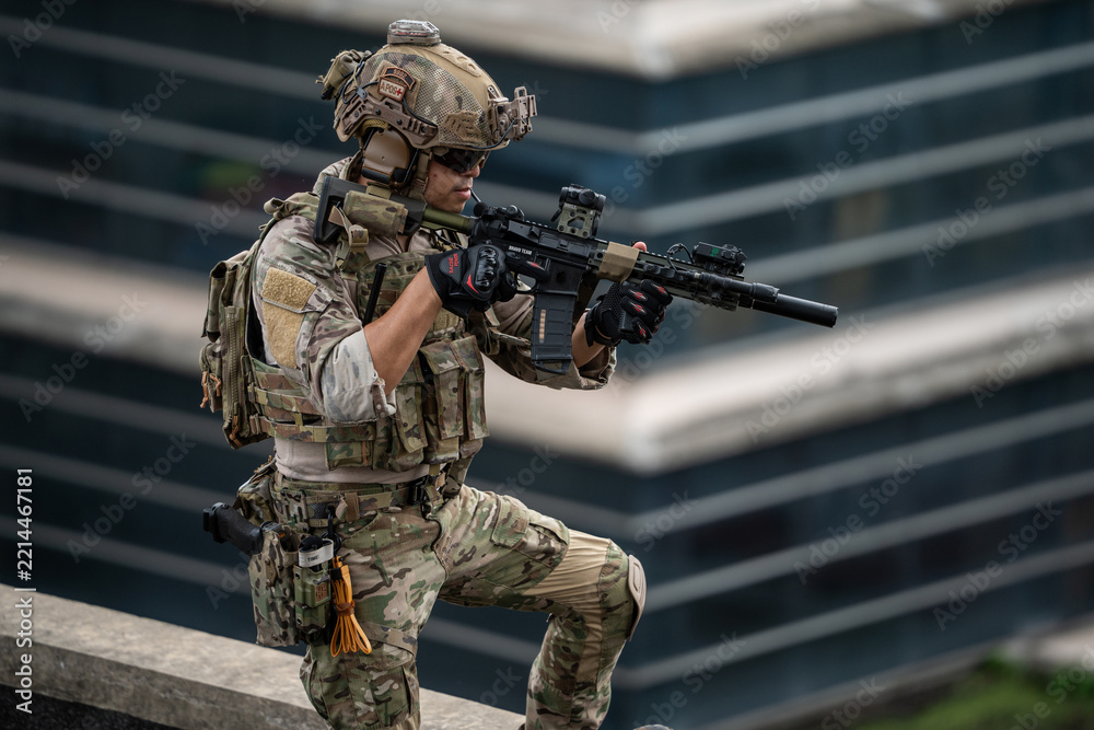 Fototapeta premium A tactical operator stands alert on a rooftop holding a rifle during an urban security operation, conveying intense focus, determination, and tactical readiness in an outdoor environment.