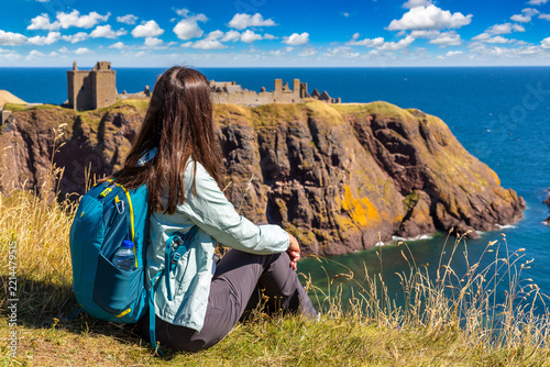 Female hiker at Dunnottar Castle ruins on sea cliffs near Stonehaven, Aberdeenshire, Scotland, UK