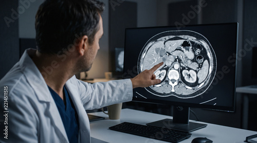 Focused doctor pointing at medical scan study diagnosis analysis screen showing abdominal health professional looking concerned