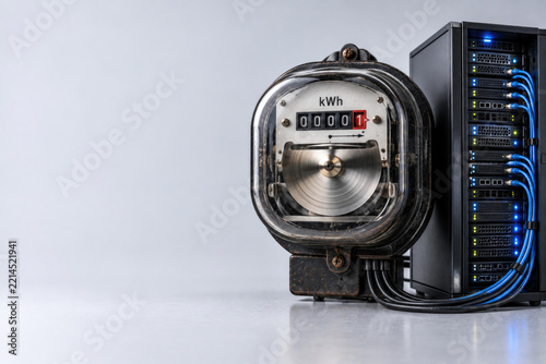 Vintage electric meter beside network server rack. Space for text.