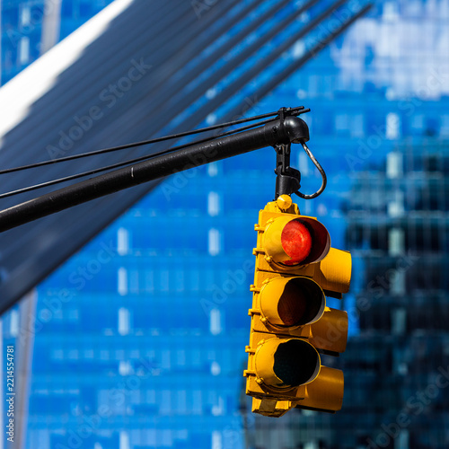 Yellow traffic signal and red light before blue glass windows