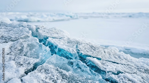 Waves of ice break apart on a frigid, icy coastline. The blue ice exhibits intricate fractures and textures.