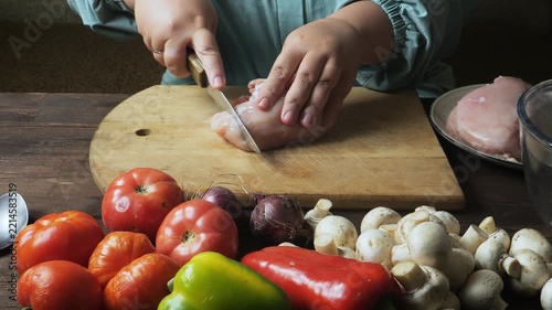 A woman's hands slice a crinot fillet on a cutting board on a table
