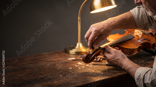 Senior Luthier Restoring Wooden Violin on Rustic Workbench under Warm Lamp Light with Copy Space