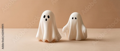 Two cute ghost Halloween decorations standing on a beige background
