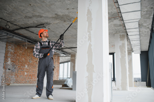 Construction worker painting walls with roller in building renovation
