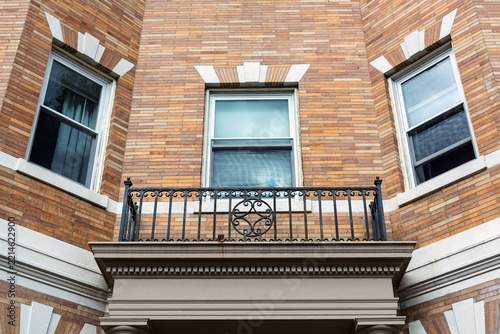 Brick building facade with decorative wrought iron balcony and windows in Boston