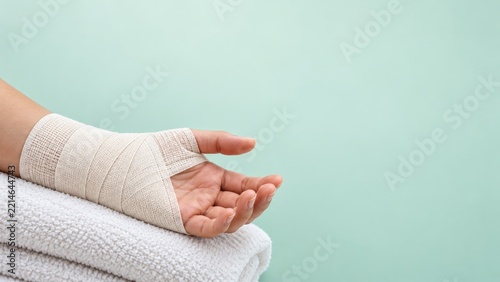 Bandaged Hand Resting Palm Up on a Folded White Towel against a Mint Background