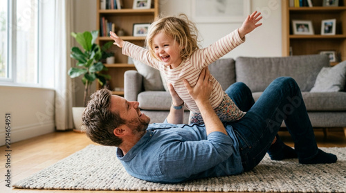 Happy father playing with daughter, lifting her up like airplane indoors