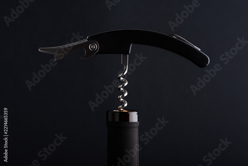 Elegant corkscrew opening dark bottle top in studio lighting with dramatic dark background