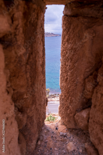 Sea view through narrow arrow slit in stone fortress wall