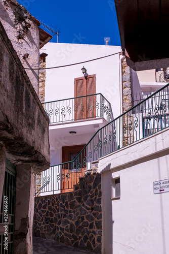 Whitewashed village house with iron staircase under blue sky