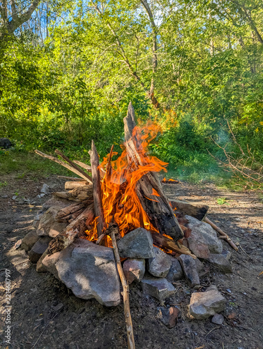 Warsaw, Poland,May 03, 2026. Vivid orange campfire fire flames dancing on burning logs in forest stone hearth. High quality photograph