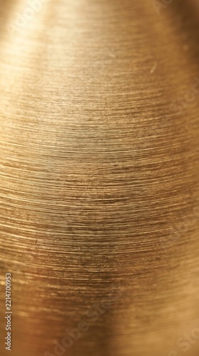 Closeup of a textured metallic surface with a warm golden hue and fine horizontal lines