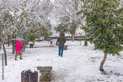 People Walking in Snow Covered Park in Winter