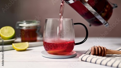 Cozy warm tea preparation with honey and lemon, pouring hot tea in glass cup from french press