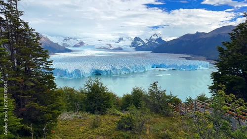 Scenic view of the massive Perito Moreno Glacier flowing into the lake surrounded by mountains and trees in Patagonia