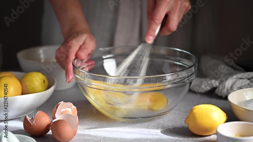 Woman whisking lemon cake batter in a glass bowl