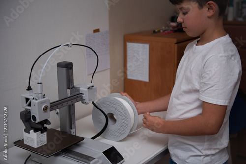 Curious boy using a modern 3D printer at home.