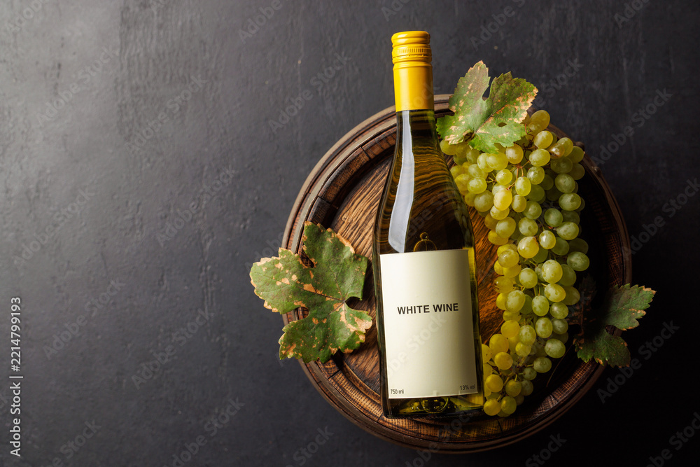 Naklejka premium Wine bottle nestled beside a ripe green grape cluster
