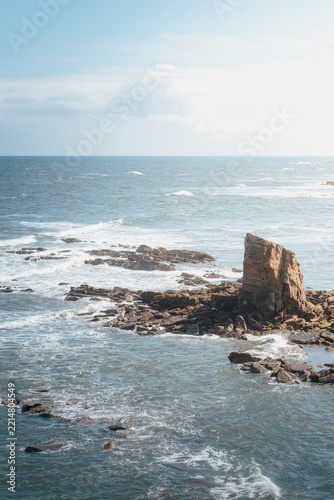 Sunlit coastal rock formations and tidal pools across Collywell Bay, Northumberland, captured during bright August 2026 shoreline conditions