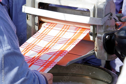 Old woman hands feeding cloth into industrial machine