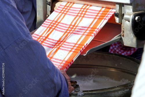 Old woman hands feeding cloth into industrial machine