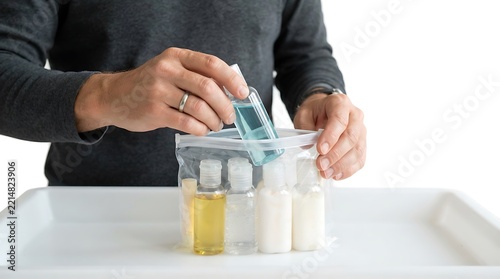 Traveler organizing small liquid containers into a clear plastic bag for airport security check