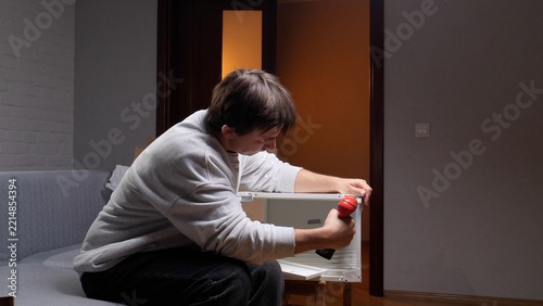 Obraz na plátně Man focusing on home improvement project, assembling new furniture with an elect