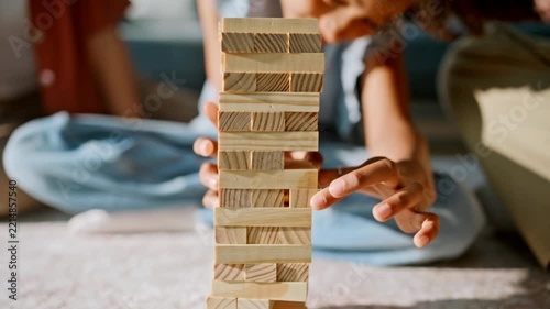 Smiling kid pulling wooden block from tower. Close up family board game home.