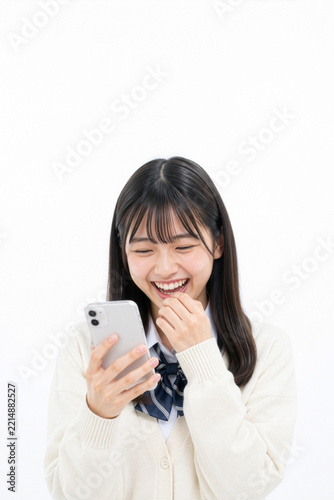 白背景でスマホのAIに話しかけ笑顔を見せる日本の女子高生