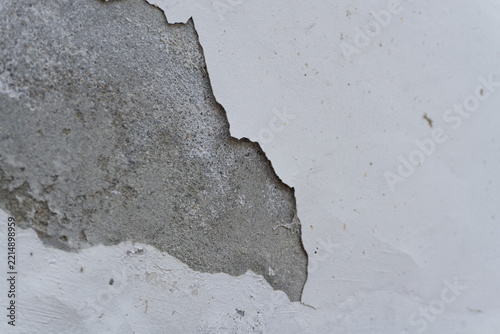 Peeling white paint revealing rough concrete wall texture