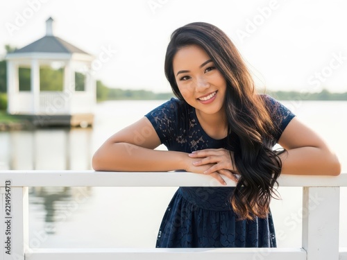 Young woman smiling by a lake with a picturesque gazebo