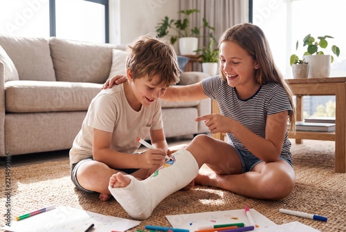 Children Drawing on Orthopedic Leg Cast in Living Room at Home