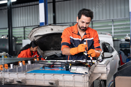 Mechanic man repairing electric vehicle battery in garage