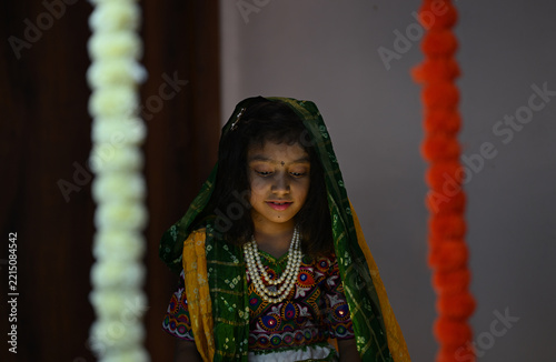 Portrait of a young Indian girl wearing traditional Gujarati ethnic clothing, she is looking down in warm cinematic lighting, creating a peaceful and elegant cultural portrait.