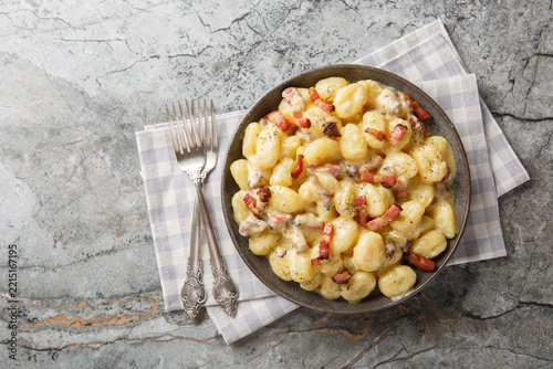 rich and creamy gnocchi carbonara made with homemade pillowy gnocchi and tossed in an easy carbonara sauce with pancetta closeup on the plate on the table. Horizontal top view from above