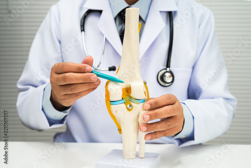 Asian doctor holding spinal nerve and bone model, Lumbar spine displaced herniated disc fragment for treatment medical in the orthopedic department.