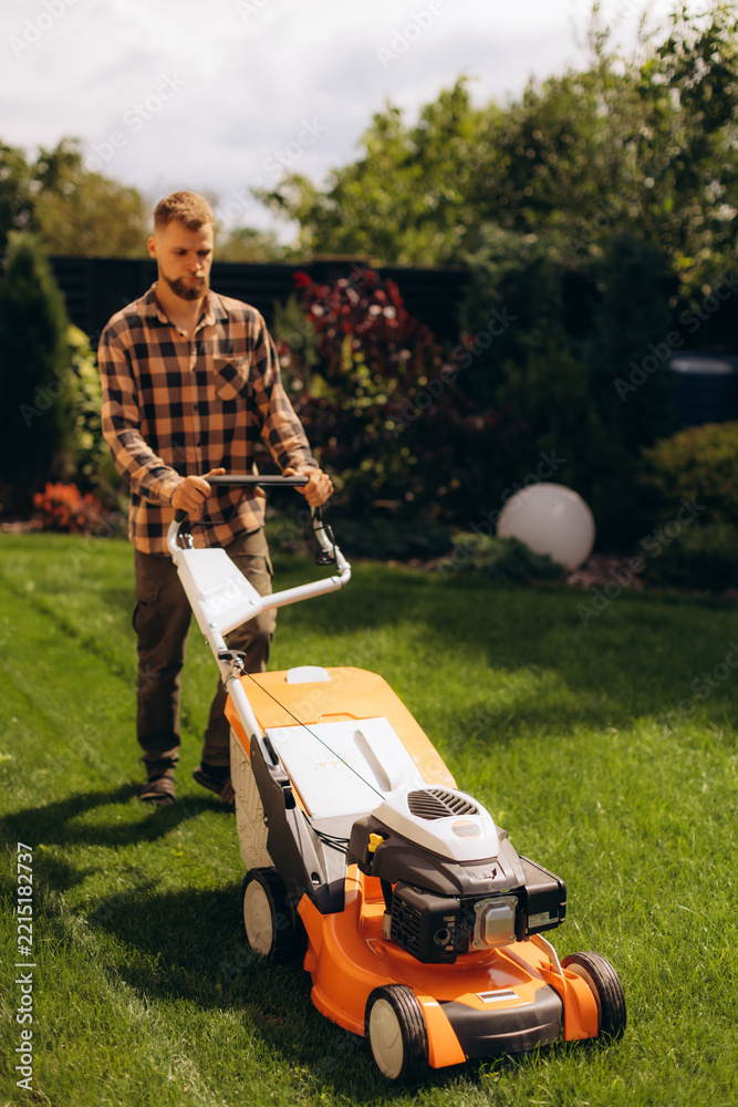 Fototapeta premium Man mowing lush green backyard grass