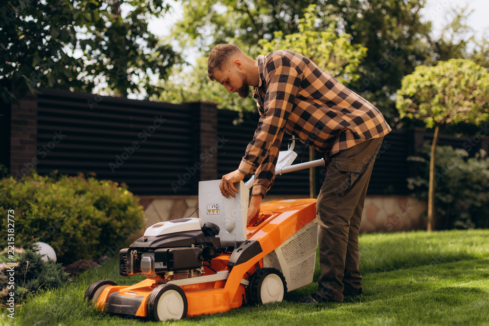 Fototapeta premium Man preparing lawn mower for yard work