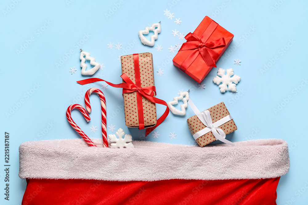 Fototapeta premium Santa bag with gift boxes, candy canes and Christmas trees on blue background