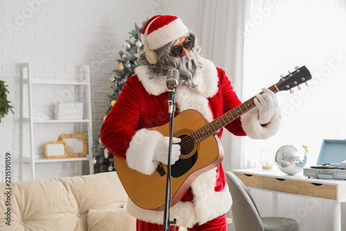 Cool Santa Claus with guitar and microphone singing at home