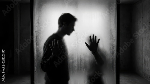Silhouette of man and woman touching glass pane from opposite sides dark mysterious mood atmospheric cinematic monochrome thriller drama scene