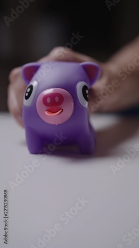 Purple squeaky pig anti stress toy sticking tongue out when squeezed by hand, playful and humorous sensory fidget tool for stress relief and fun entertainment, close-up, vertical slow motion.